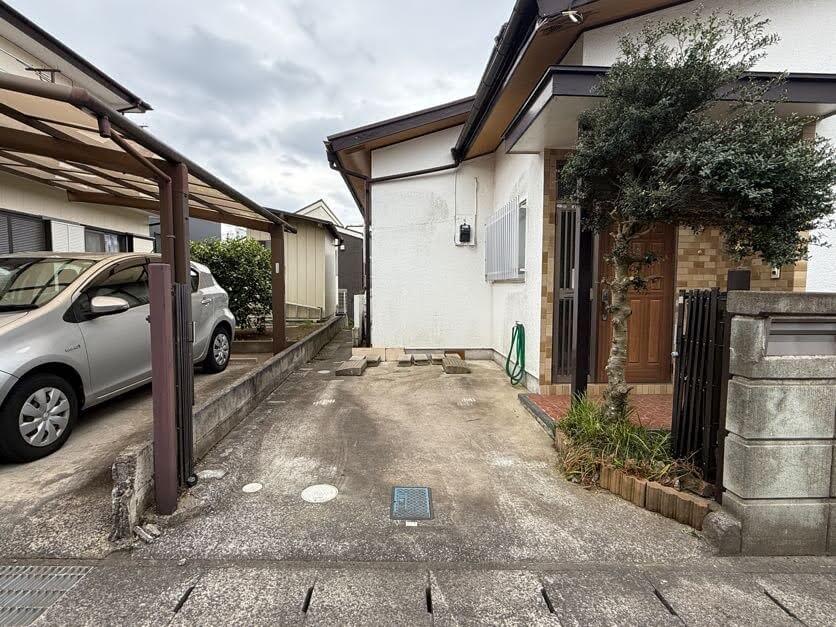 千葉市中央区赤井町の売地の敷地内の様子。コンクリート敷の駐車スペースと、建物の側面が写っている。
