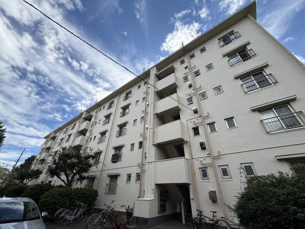 晴れた日の青空の下に建つ「相模台団地」の外観。自転車置き場や植栽も整備されている。