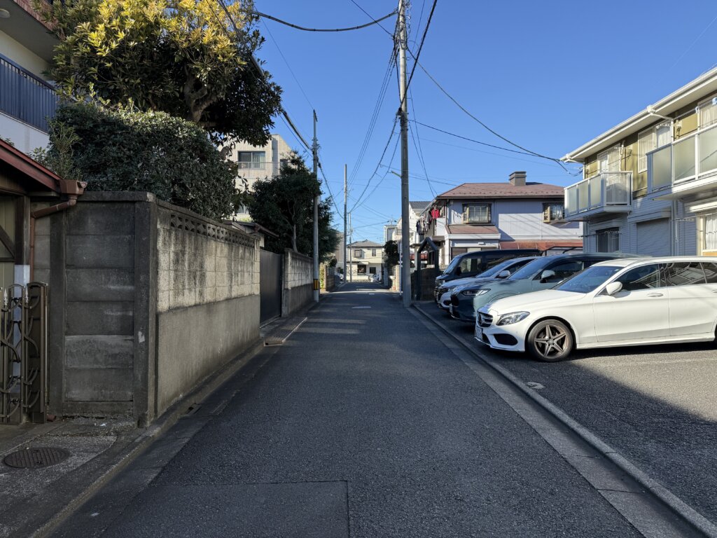 接面道路（公道）の様子。周辺は閑静な住宅街で、前面道路は車がすれ違える幅員がある。