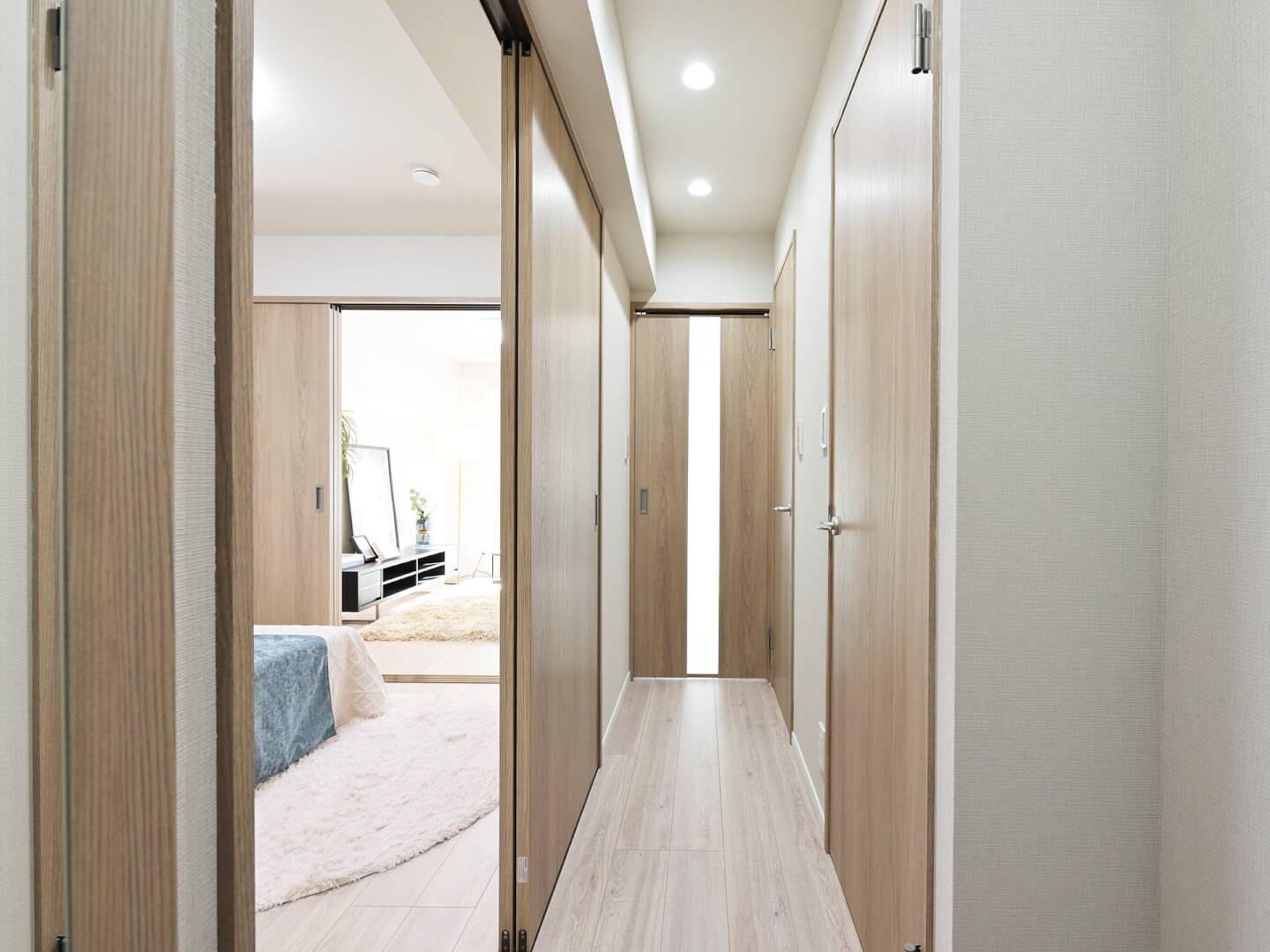 廊下からリビングダイニングへ続く動線。引き戸を開放することで、リビングの窓まで視線が抜け、空間の広がりを感じられる。