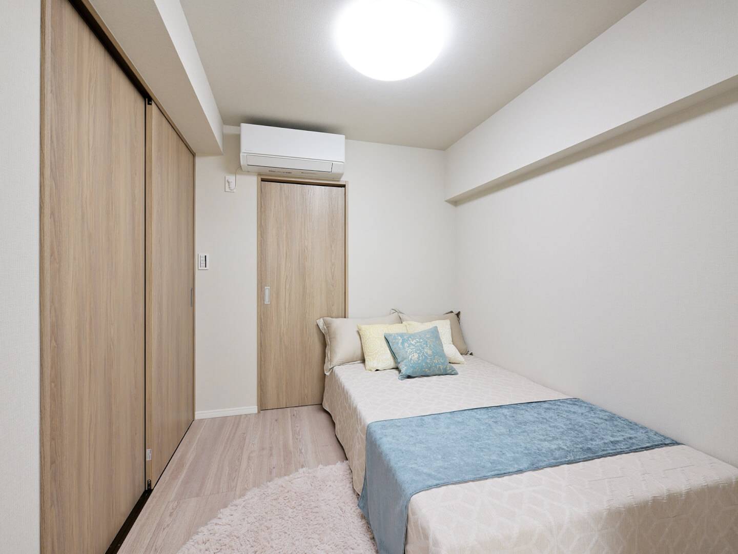 ベッドが配置された洋室。明るい木目調の建具で統一されており、落ち着いて休める空間。壁面には大容量のクローゼットが備え付けられている。