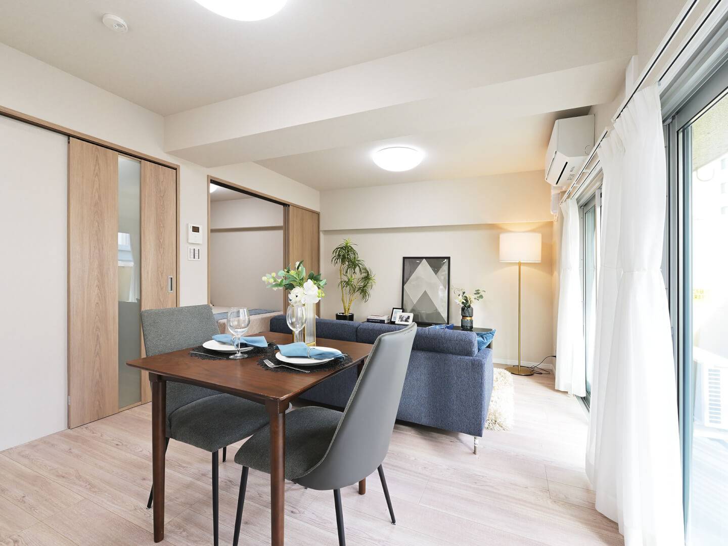 ダイニングスペースからリビング、そして隣接する洋室までを見渡した様子。引き戸を開け放つことで、各空間が緩やかにつながり、一体感のある広々とした空間になる。