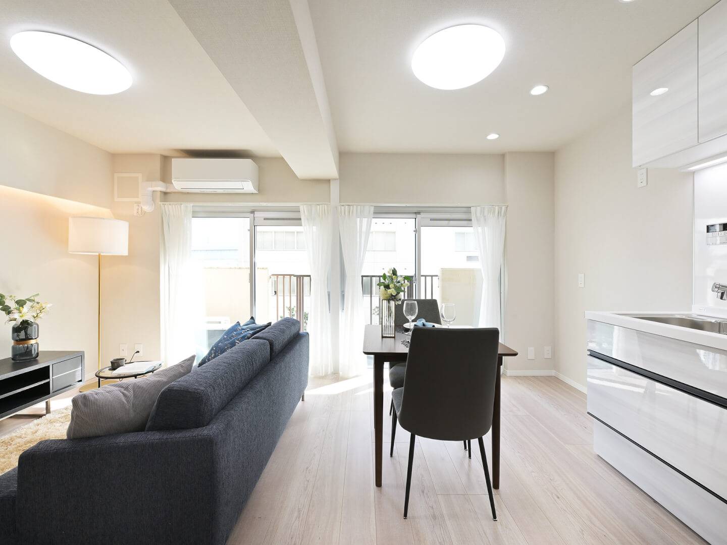 東向きの窓から明るい朝日が差し込むリビングダイニング。ソファやダイニングテーブルが配置され、単身やDINKSの実際の生活をイメージしやすい空間。