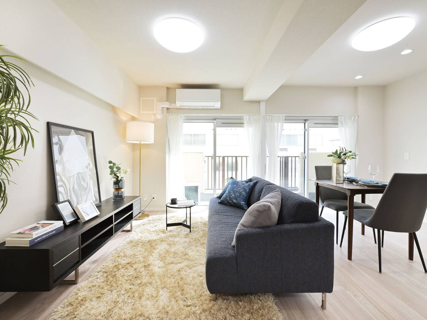 リビングダイニングの様子。壁際にローボードが置かれ、その前にソファが配置されている。大きな窓からは自然光がたっぷりと入り、明るく開放的な雰囲気。