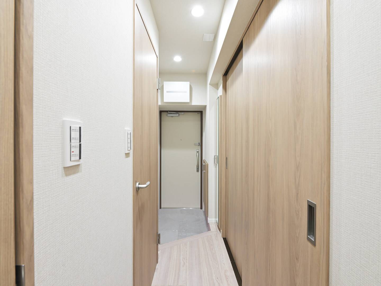 フルリノベーションされた玄関から廊下を見た内観写真。明るい木目調の建具が並び、清潔感と温かみのある空間。