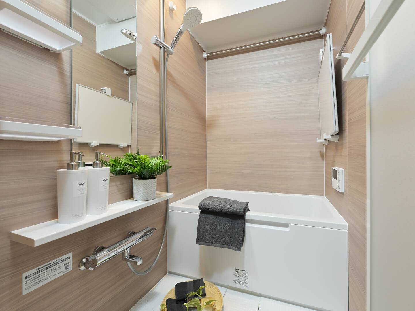 木目調の壁面パネルが落ち着いた雰囲気を演出するバスルーム。浴室乾燥機やスライドバー付きシャワーなど、充実した設備が備わっている。